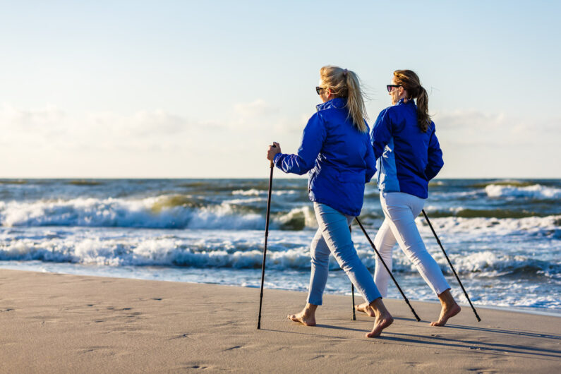 Dwie kobiety uprawiają nordic walking na plaży