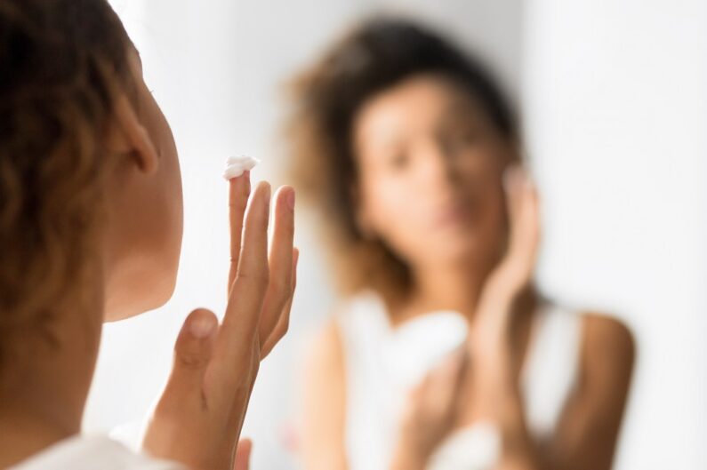Kobieta przed lustrem nbakłada na twarzkem z witaminą C
