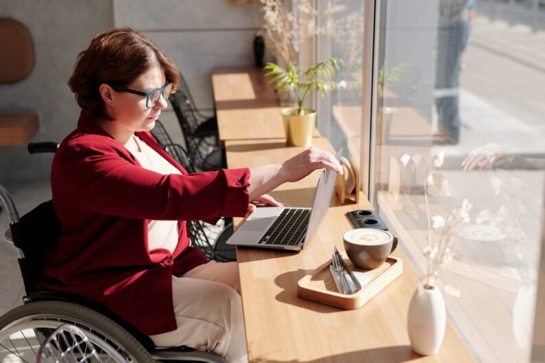 Kobieta na wóżku inwalidzkim pracuje przed laptopem